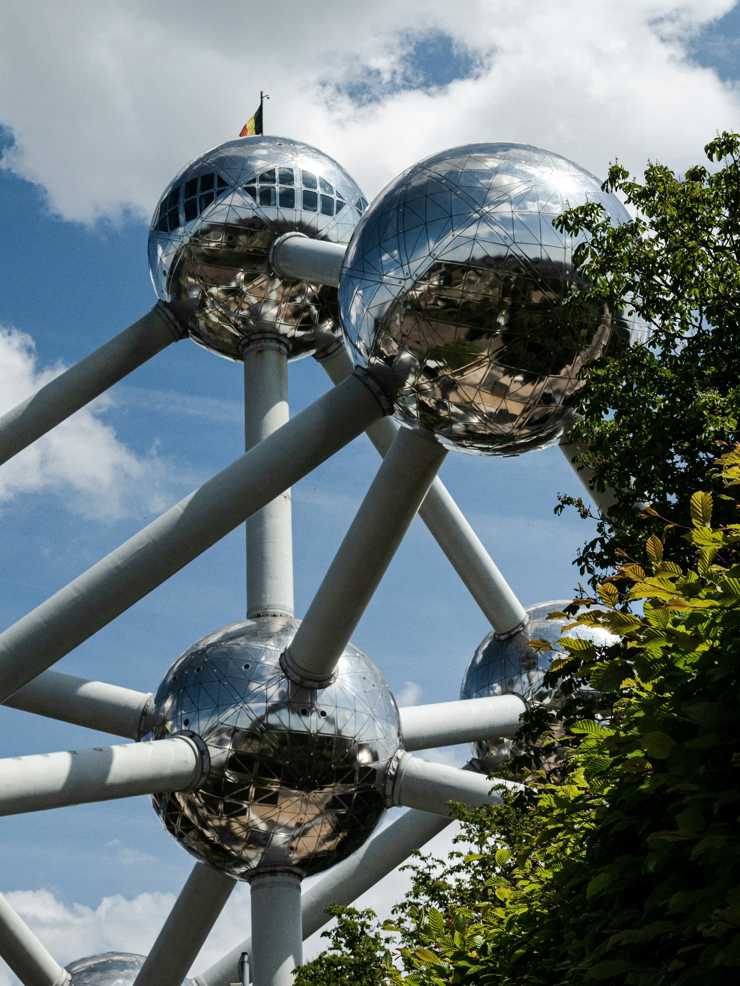 Reflective steel spheres of the Atomium connected by tubes against a blue, cloudy sky.